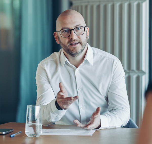 Leidinggevende man in wit overhemd voert een gesprek aan een bureau.