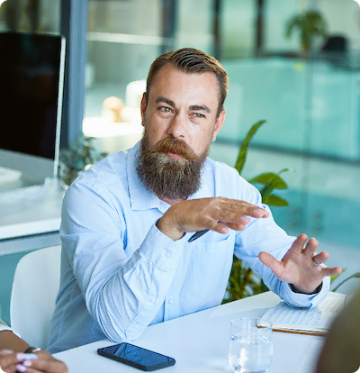 Man met baard in gesprek tijdens een vergadering op kantoor.