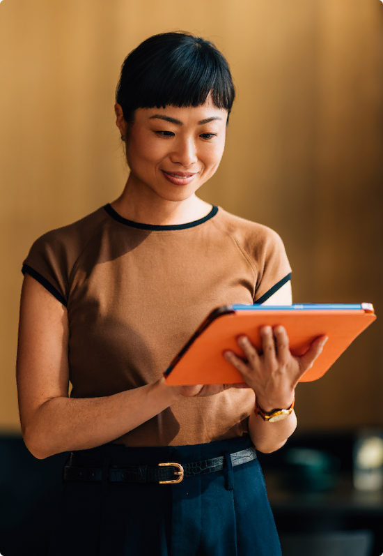 Vrouw leest staand van een iPad die ze in haar hand houdt.