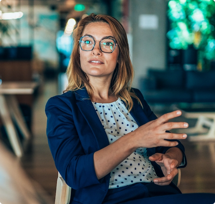 Zakelijke vrouw met bril luistert aandachtig tijdens een gesprek op kantoor.
